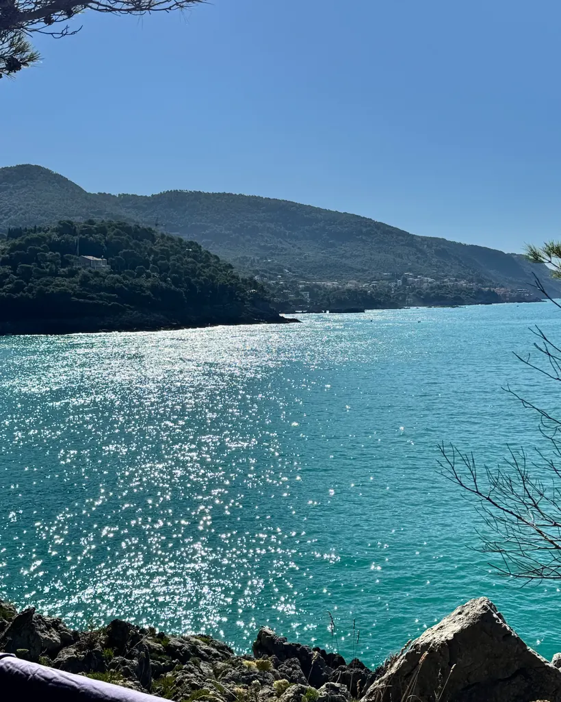 Riflessi argentati del sole sul mare tra le rocce della costa.