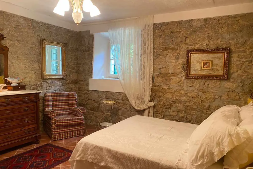 Camera d'epoca di Casa Urzano con arredi d'altri tempi e letto in ferro battuto