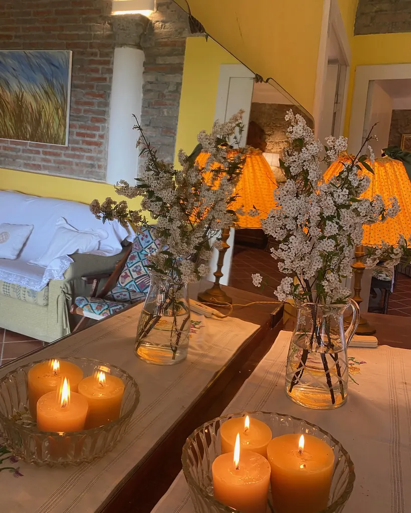 Candele accese e un mazzo di fiori di campo su un tavolo, per un'atmosfera intima e raccolta.