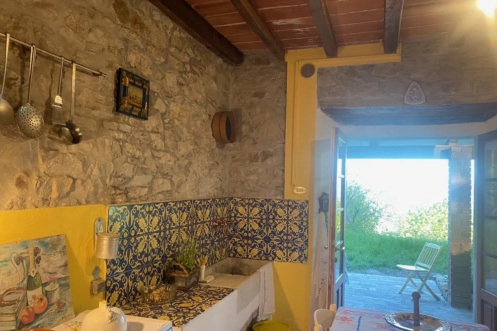 Cucina rustica con piastrelle in maiolica decorata e muri in pietra a vista, dal sapore antico.