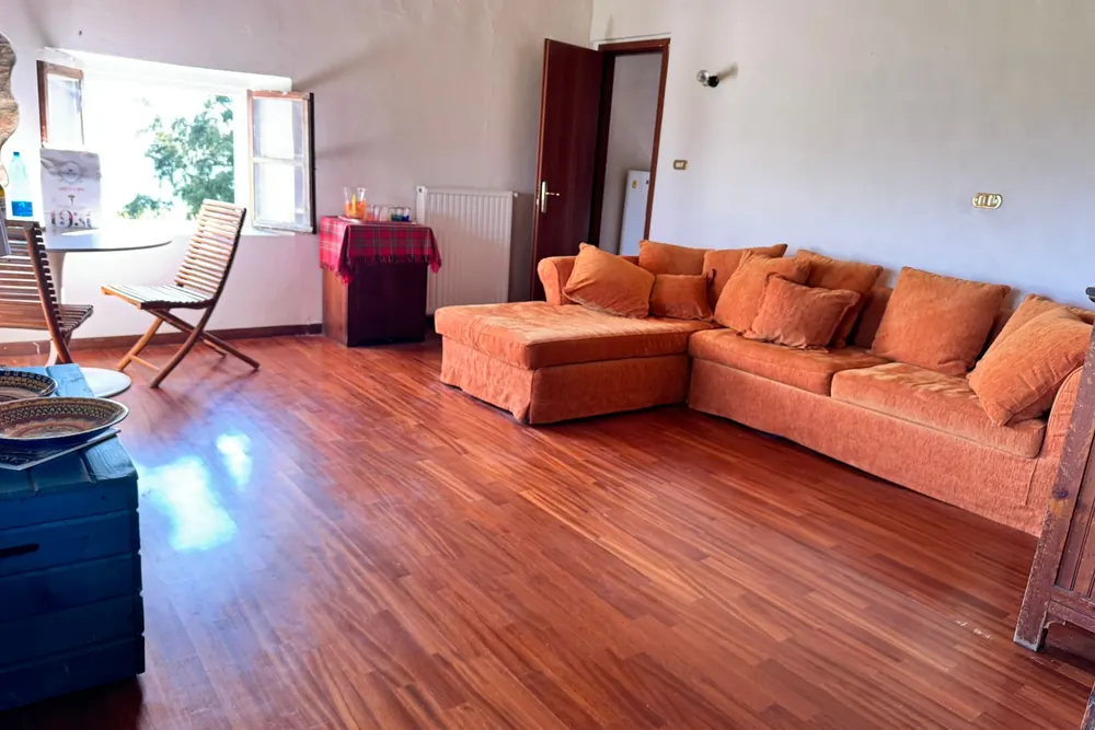Ampio soggiorno dai toni caldi, con divani e travi a vista, luogo accogliente dove ritrovarsi in famiglia.